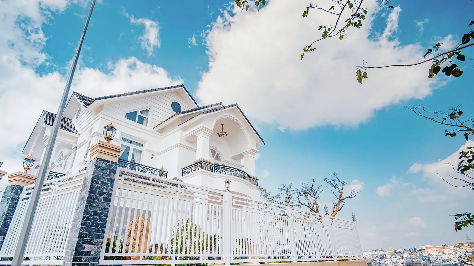 A white villa with balconies and a tiled roof against a blue Đà Lạt sky.