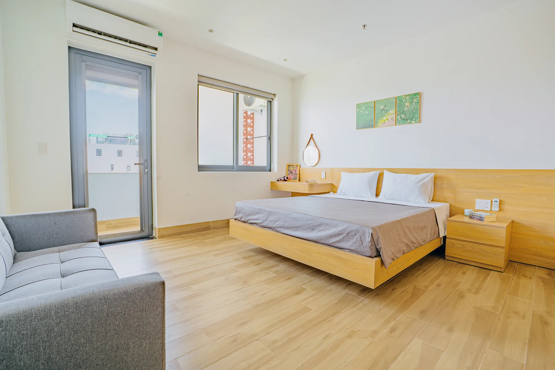 A bright bedroom with a balcony door and a sofa along the wall.