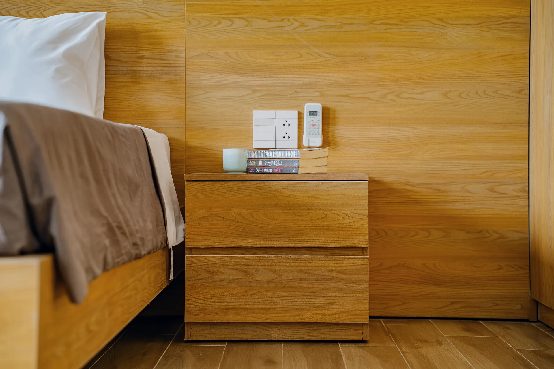 A bedside detail: timber headboard, nightstand and folded throw.